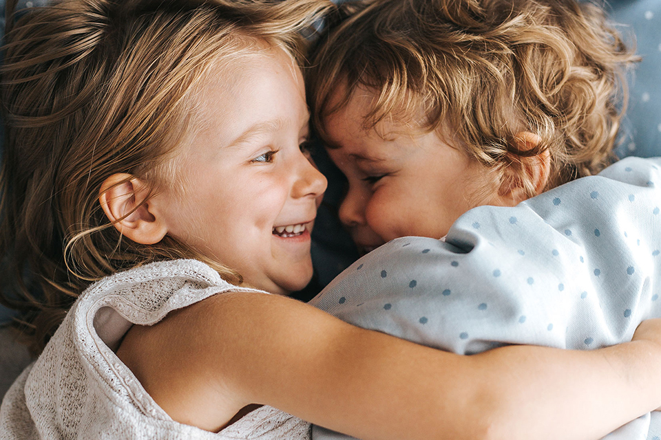 Zwei Kinder umarmen sich liebevoll und lächeln einander glücklich an