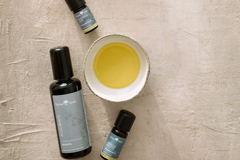 Basisöl und zwei Aromaöle neben einer mit Öl gefüllten Schale