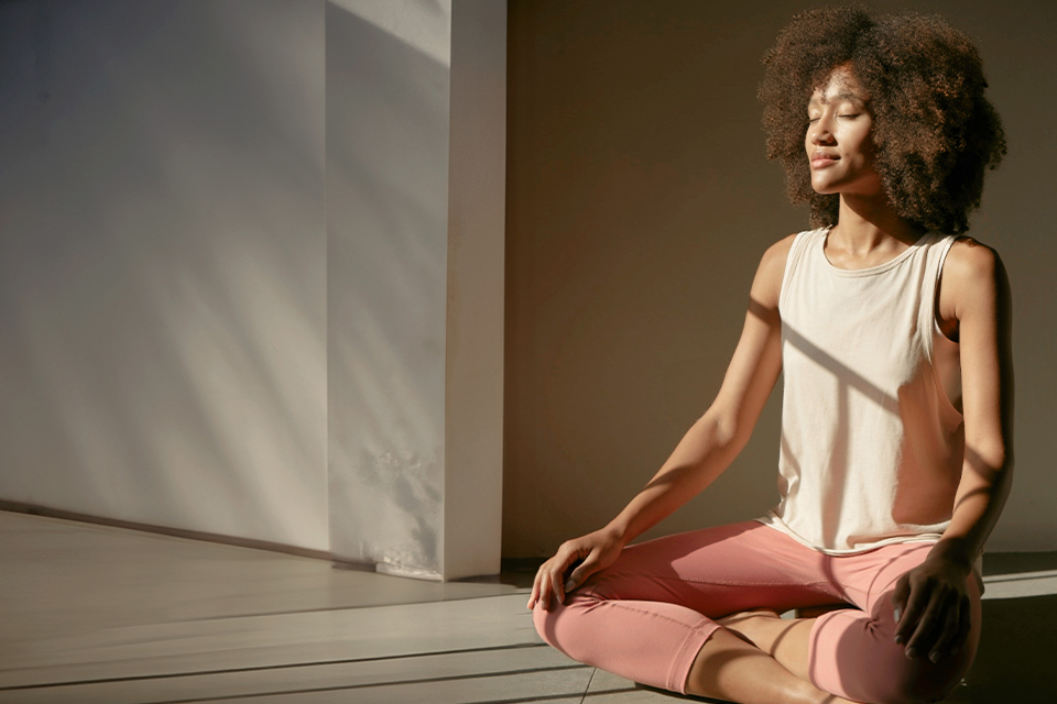 Frau meditiert entspannt im warmen Licht in ruhigem Raum