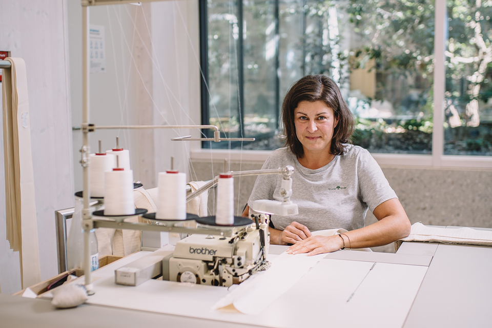 Frau arbeitet konzentriert an Tisch mit Materialien in hellem Raum