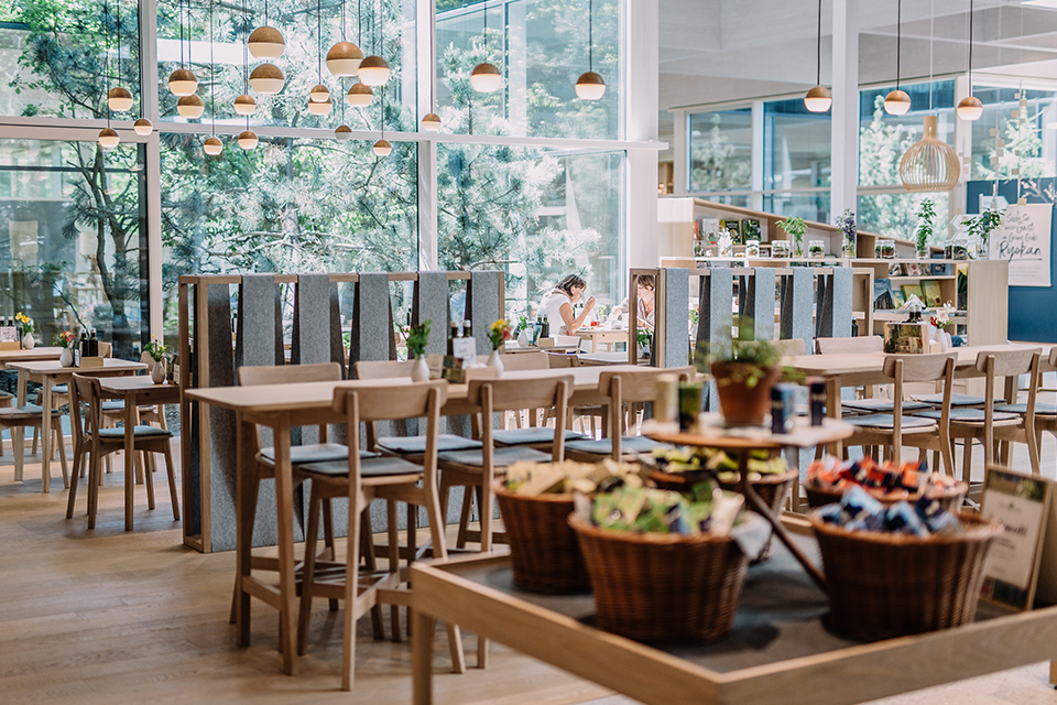 Moderner heller Innenraum mit Holztischen Sitzgelegenheiten und dekorativen Körben