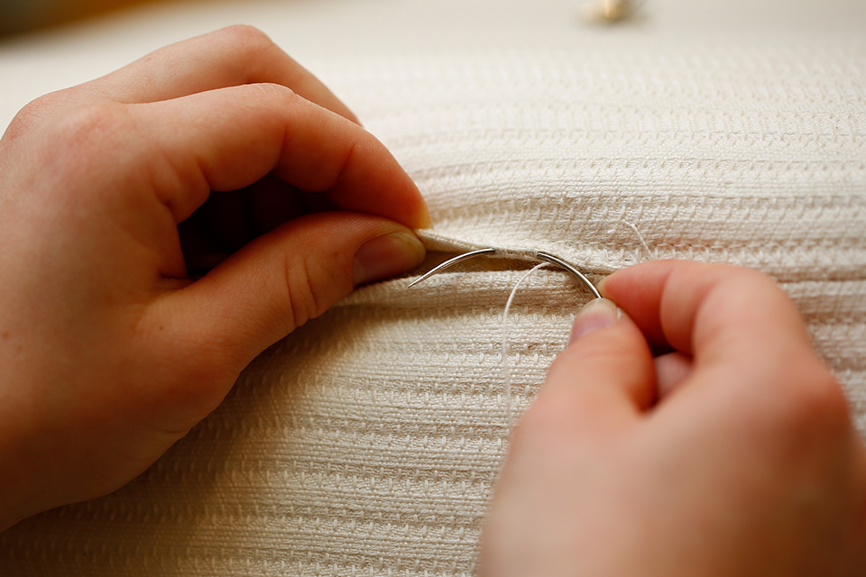 Hände nähen Naturmatratze zusammen