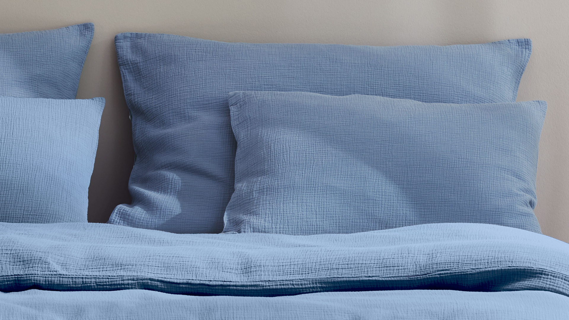 Blaue Bettwäsche auf einem Bett präsentiert