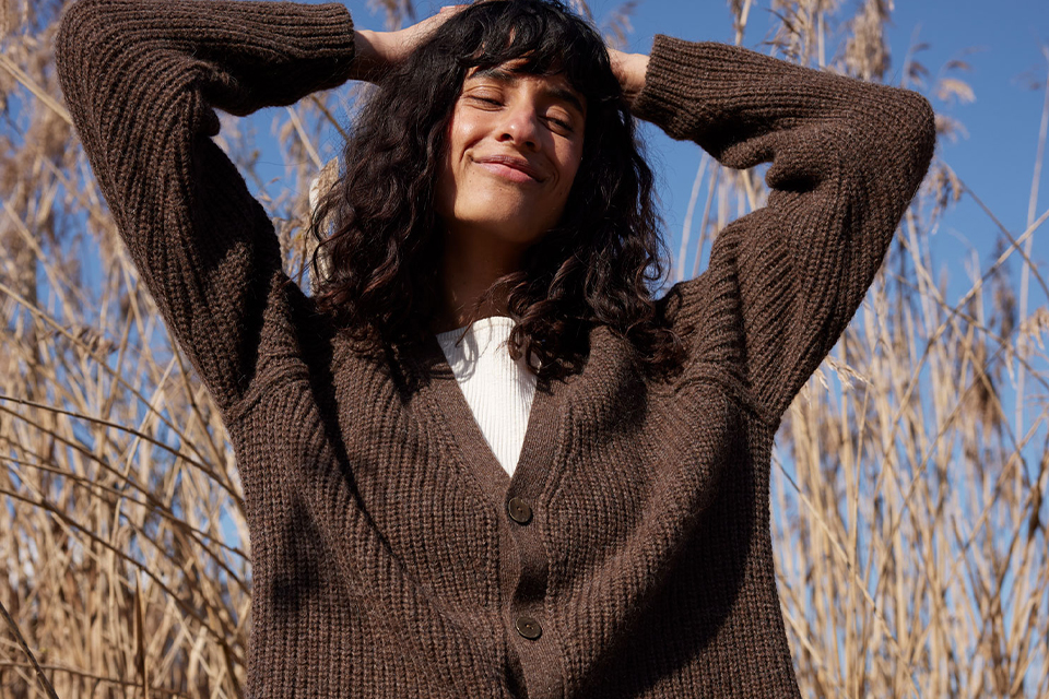 Frau in braunem Sweater steht in einem Feld