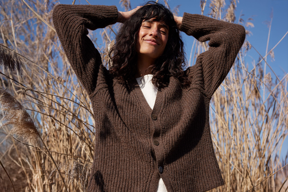 Frau im braunen Pullover genießt Sonne im Freien