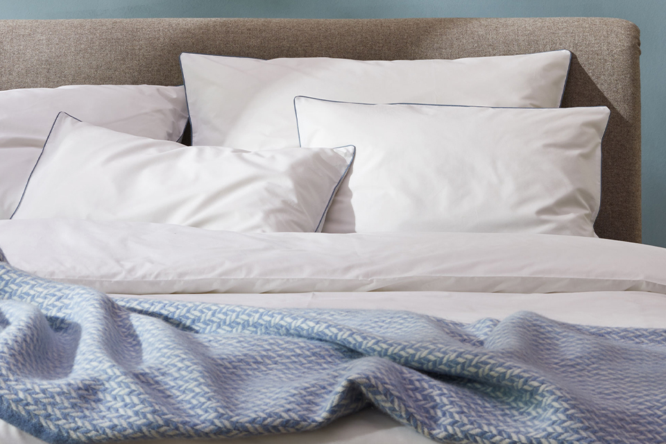 Bettwäsche Edna weiß ozean und Wohndecke Nolan auf einem Massivholzbett