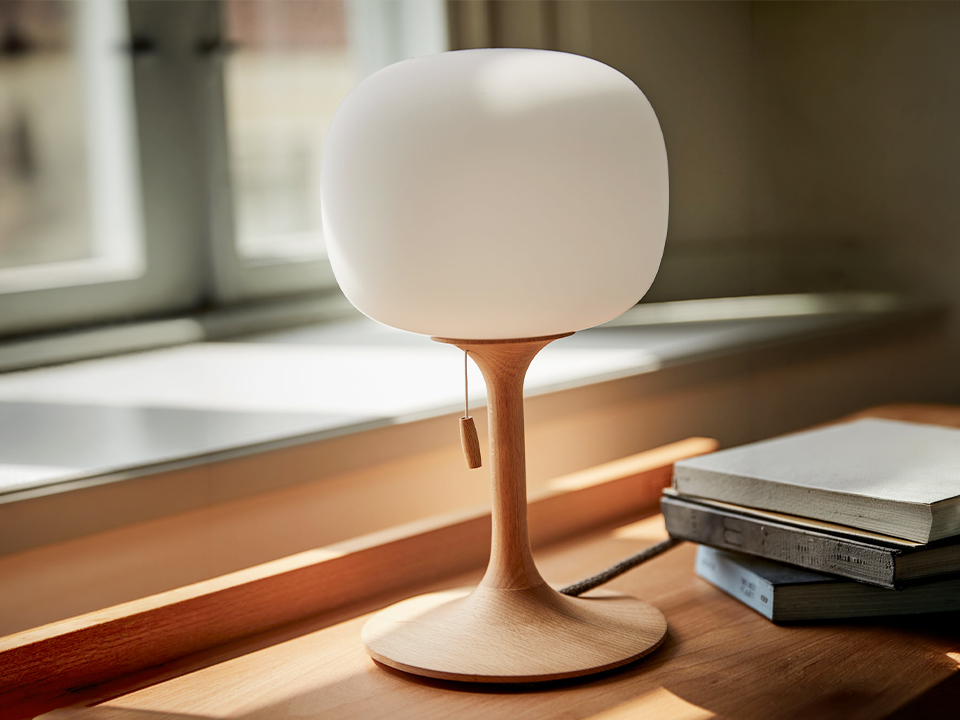 Tischleuchte Tando auf Sideboard neben Bücher