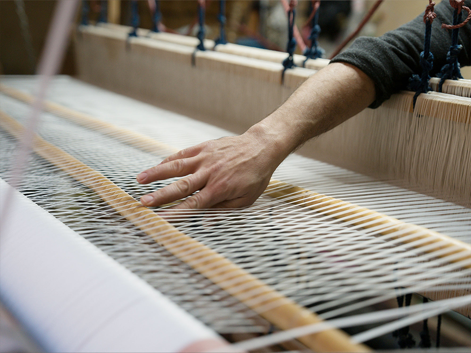 Hände beim arbeiten am Webstuhl