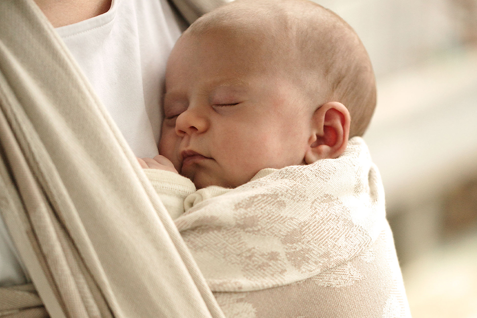 Ein Baby schläft im Tragetuch