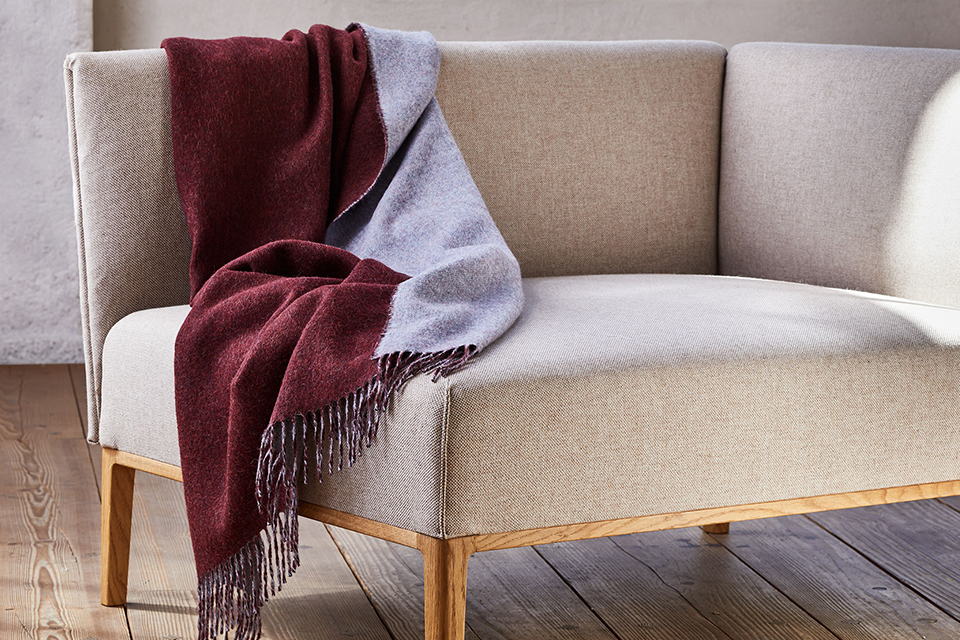 Sofa mit weicher Decke in ruhigem skandinavischem Wohnzimmer