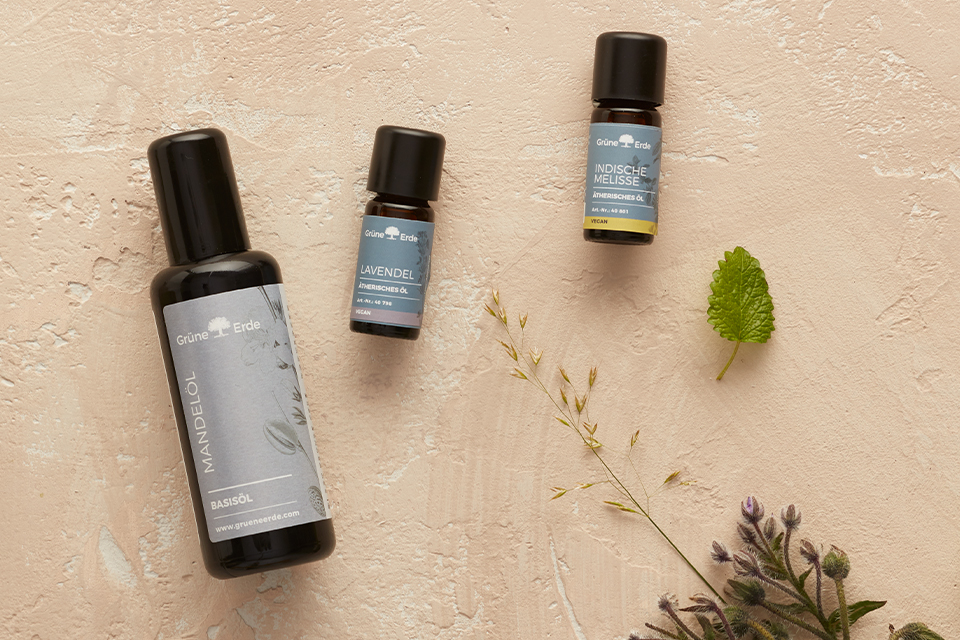 Basisöl und ätherische Öle neben dekorativen Zweigen