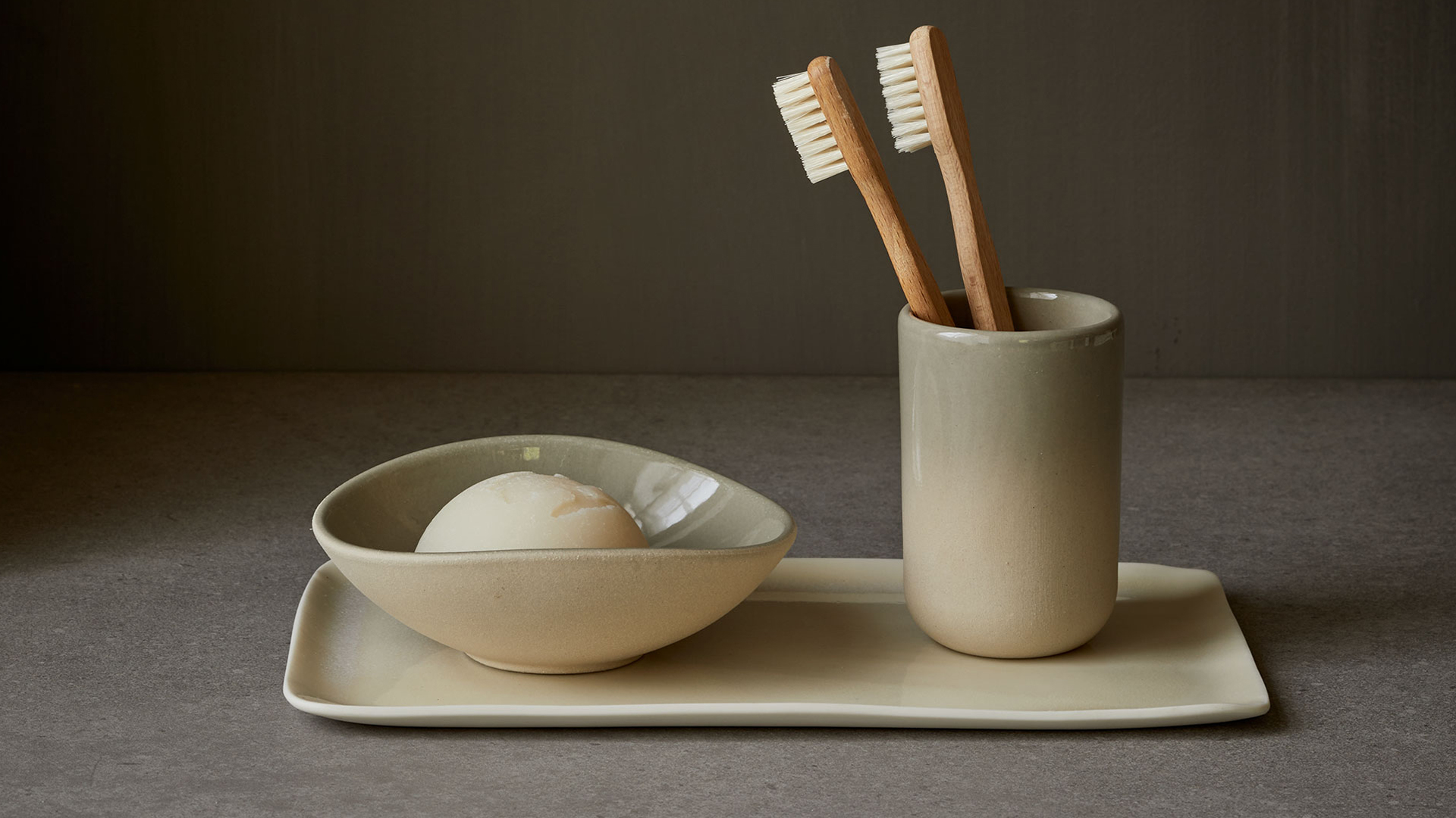 Zahnbürsten im Becher neben Seife auf minimalistischem Waschplatz