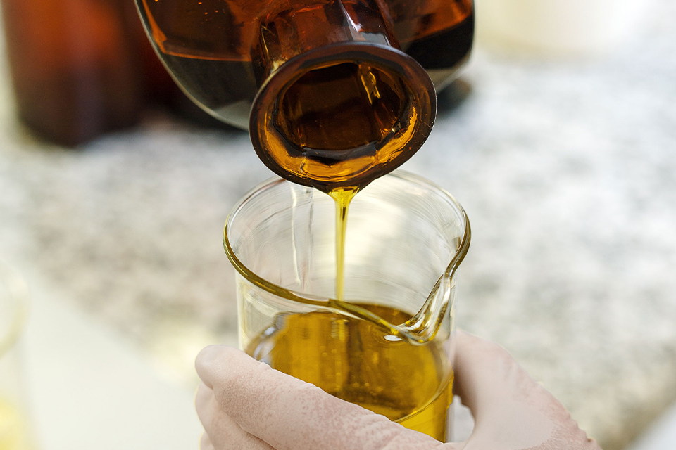 Ölartige Textur fließt aus gläsernem Behälter in Glas