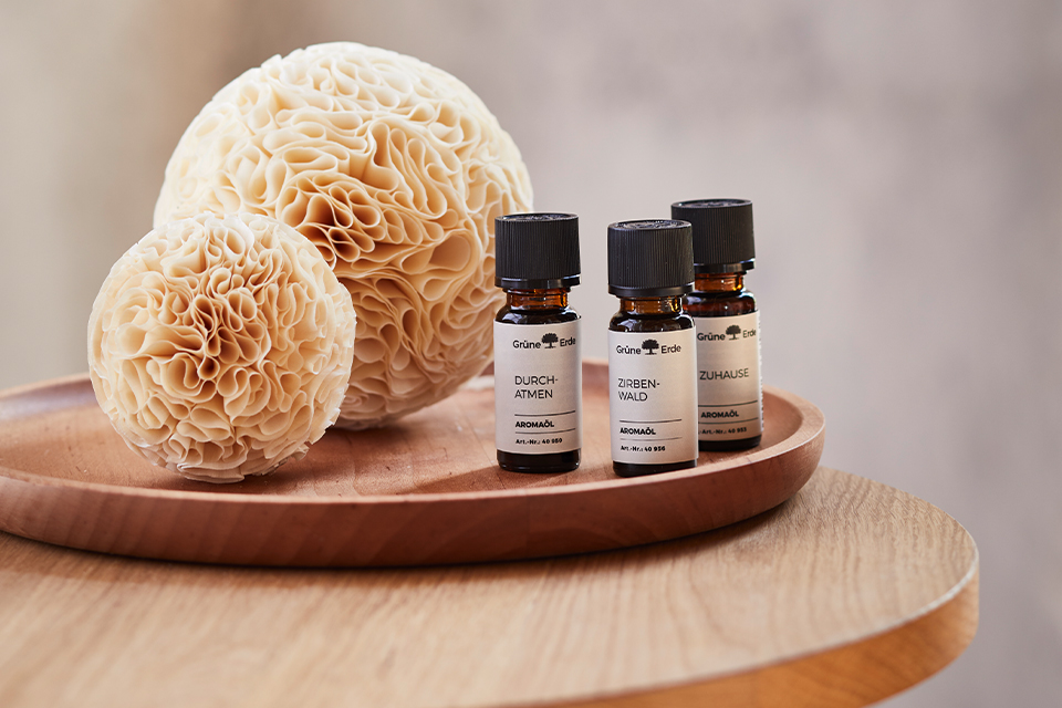 Duftkugeln aus Zirbenholz mit verschiedenen Duftölen in einer Holzschale auf einem Tisch stehend