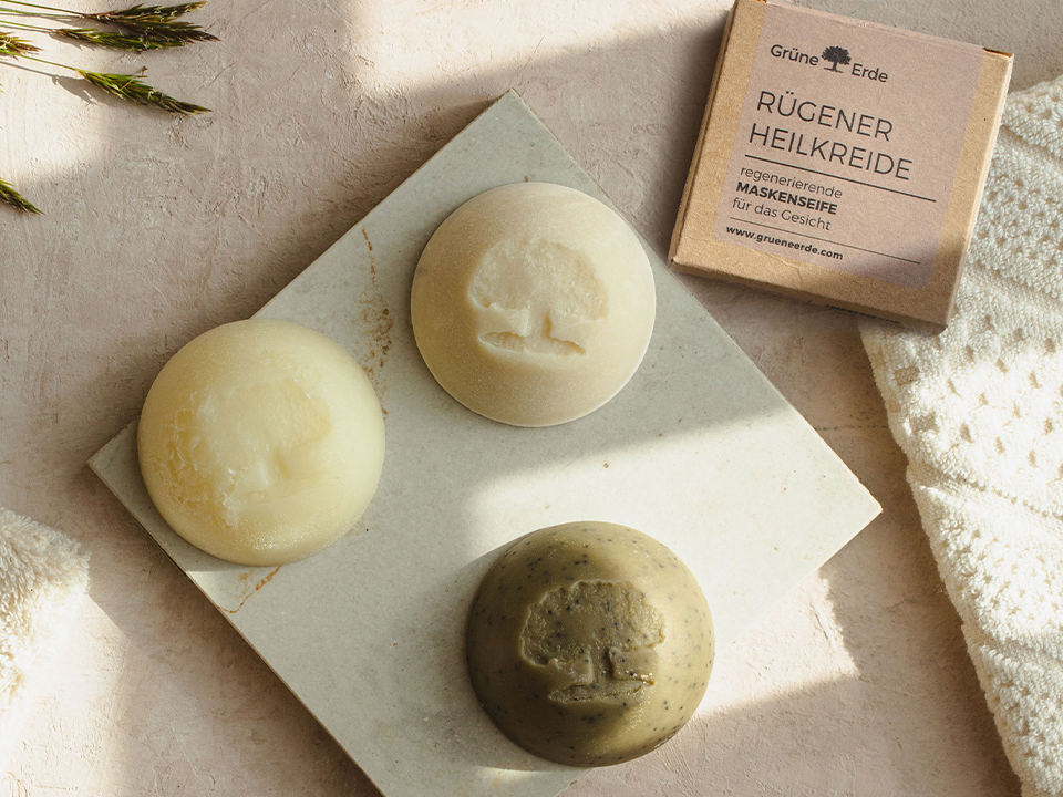 Eine Seife ein Peeling und eine Heilkreide nebeneinander liegend