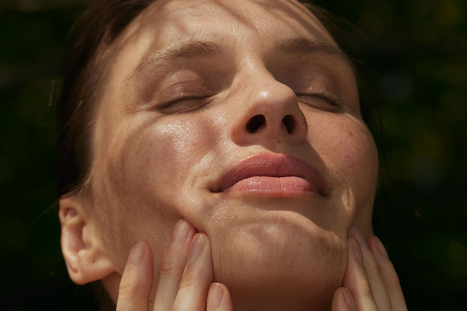 Frau trägt mit geschlossenen Augen blickt in die Sonne