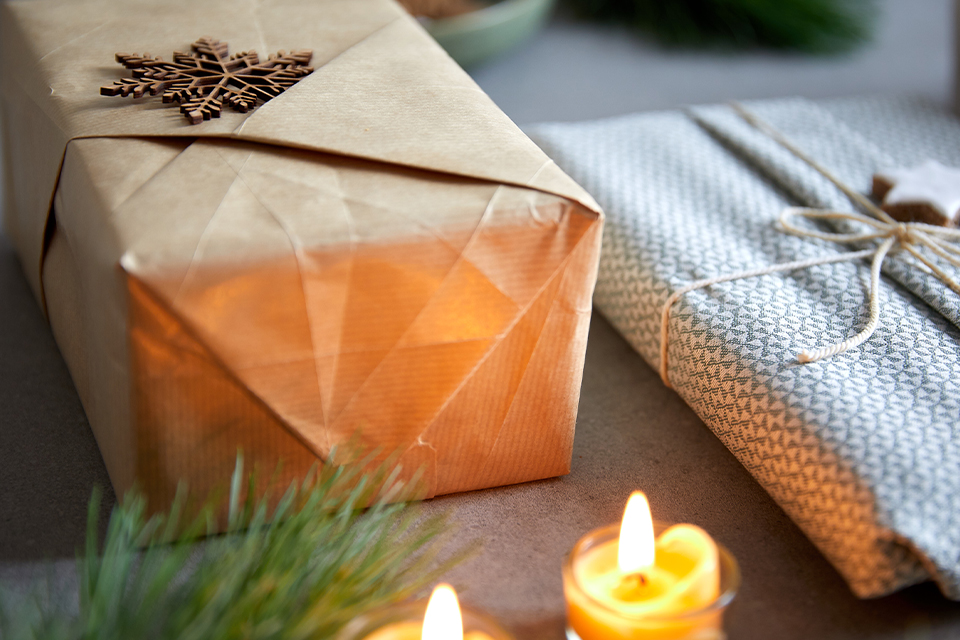 Zwei verpackte Geschenke und zwei brennende Teelichter
