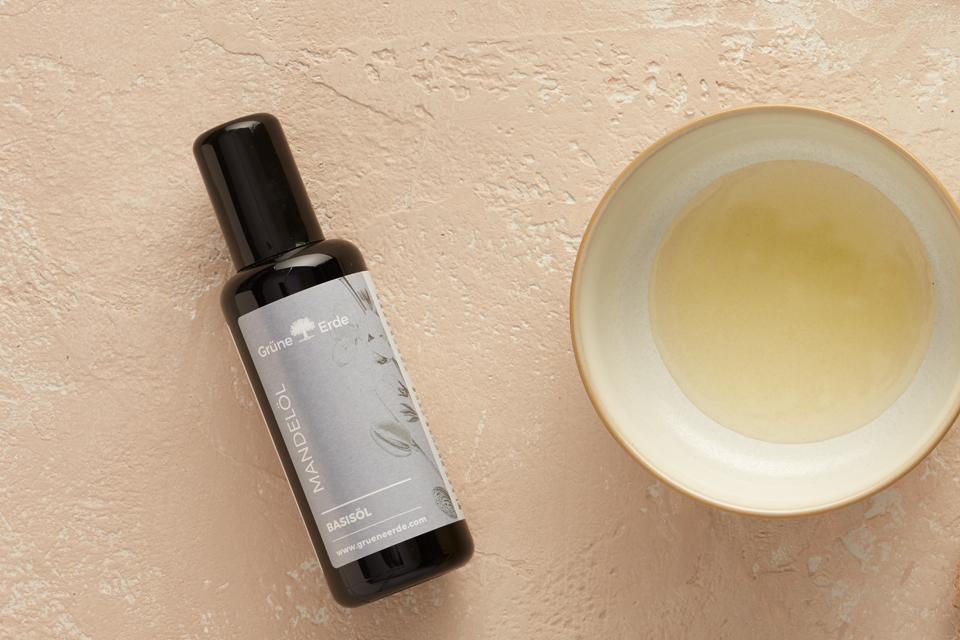 Mandelöl neben mit Öl gefüllter Keramikschale