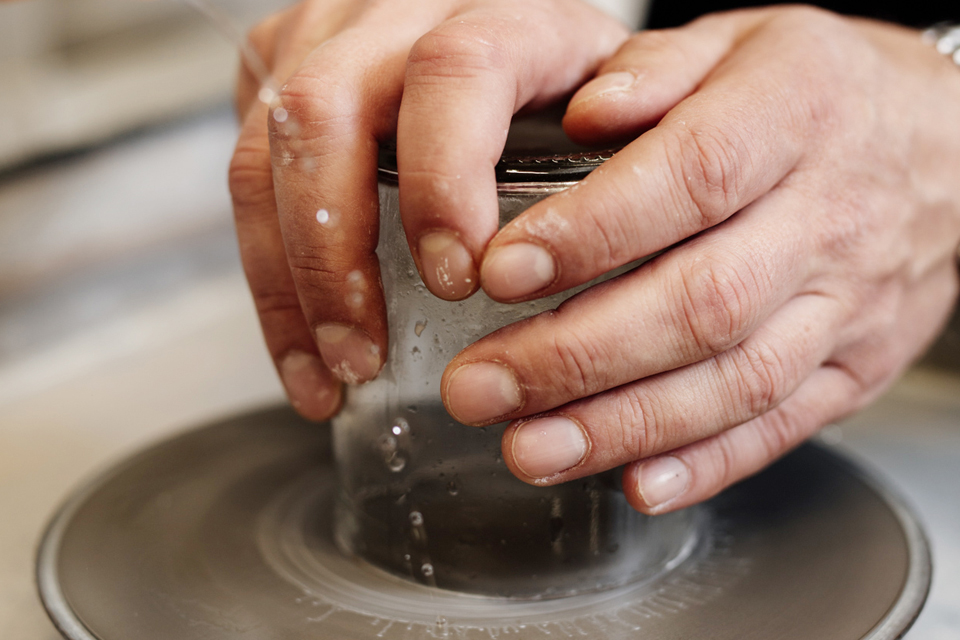 Hände formen Ton auf einer Drehscheibe in ruhiger Werkstatt