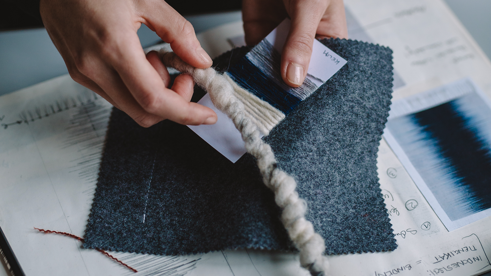 Hände halten Teppichmuster und Wollschnur