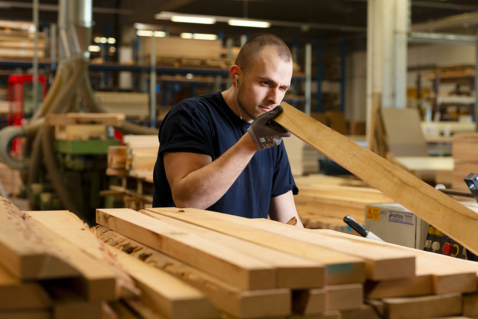 Mitarbeiter begutachtet Holzbretter