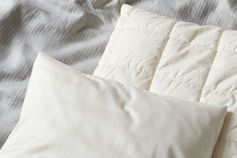 Zwei hochwertige Schlafkissen auf grauer Bettwäsche