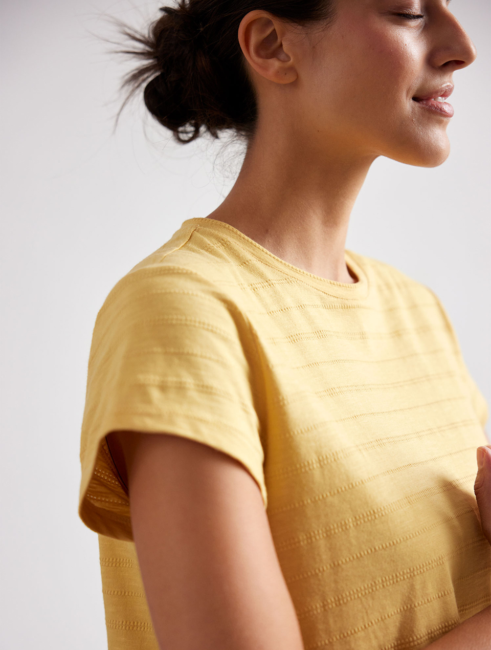 Frau mit hochgesteckten Haaren trägt gelb gestreiftes Shirt