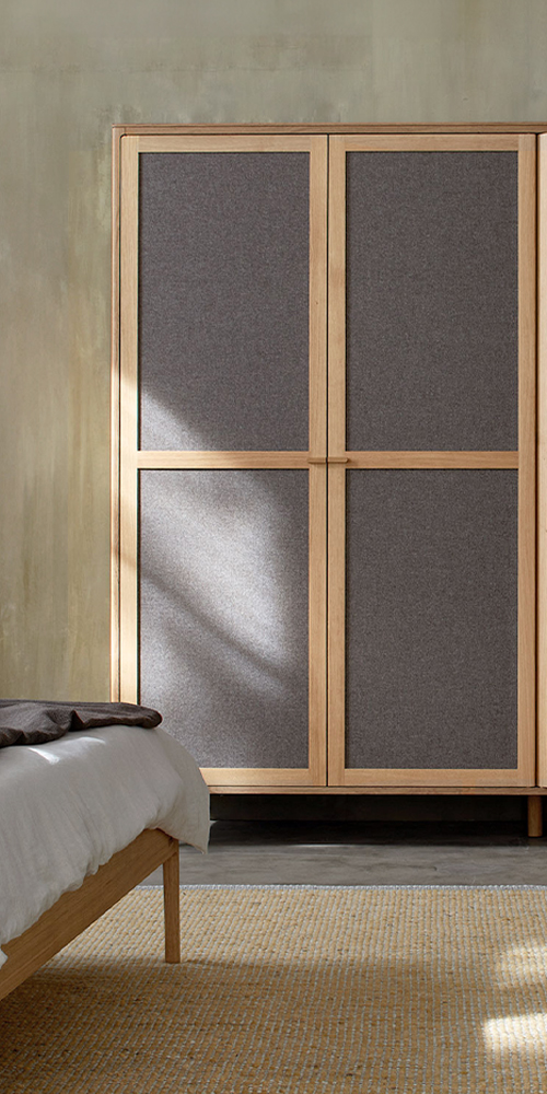 Kleiderschrank aus Massivholz mit Türfüllungen aus grauem Wollstoff