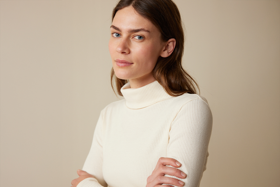 Frau in hellem Oberteil vor neutralem Hintergrund