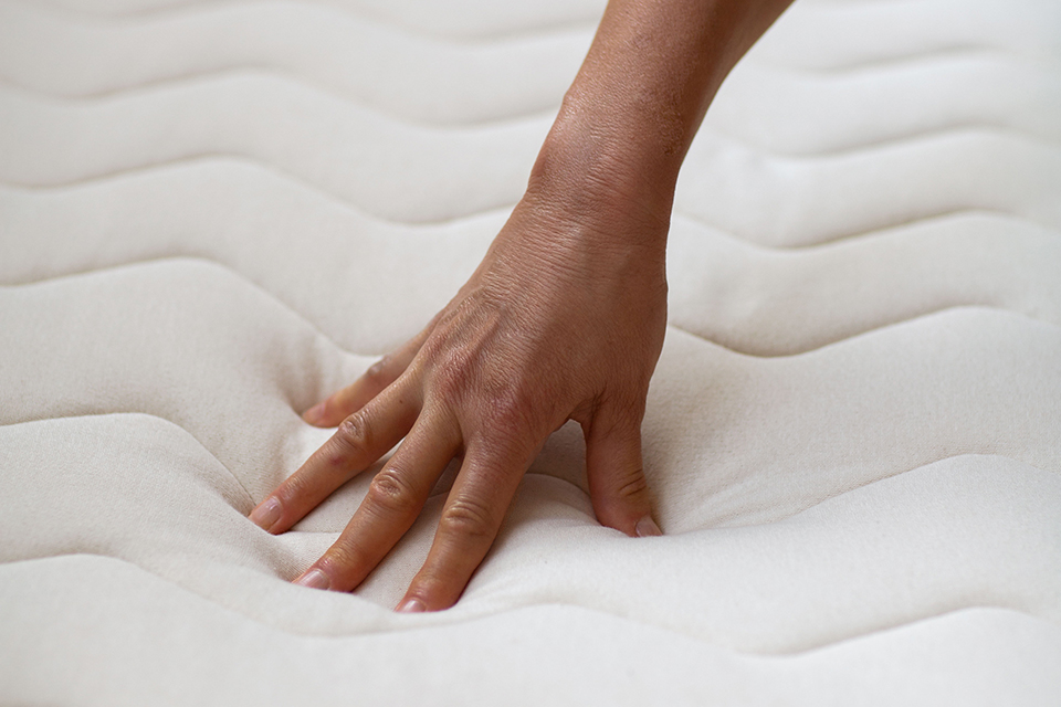 Hand drückt auf Naturmatratze