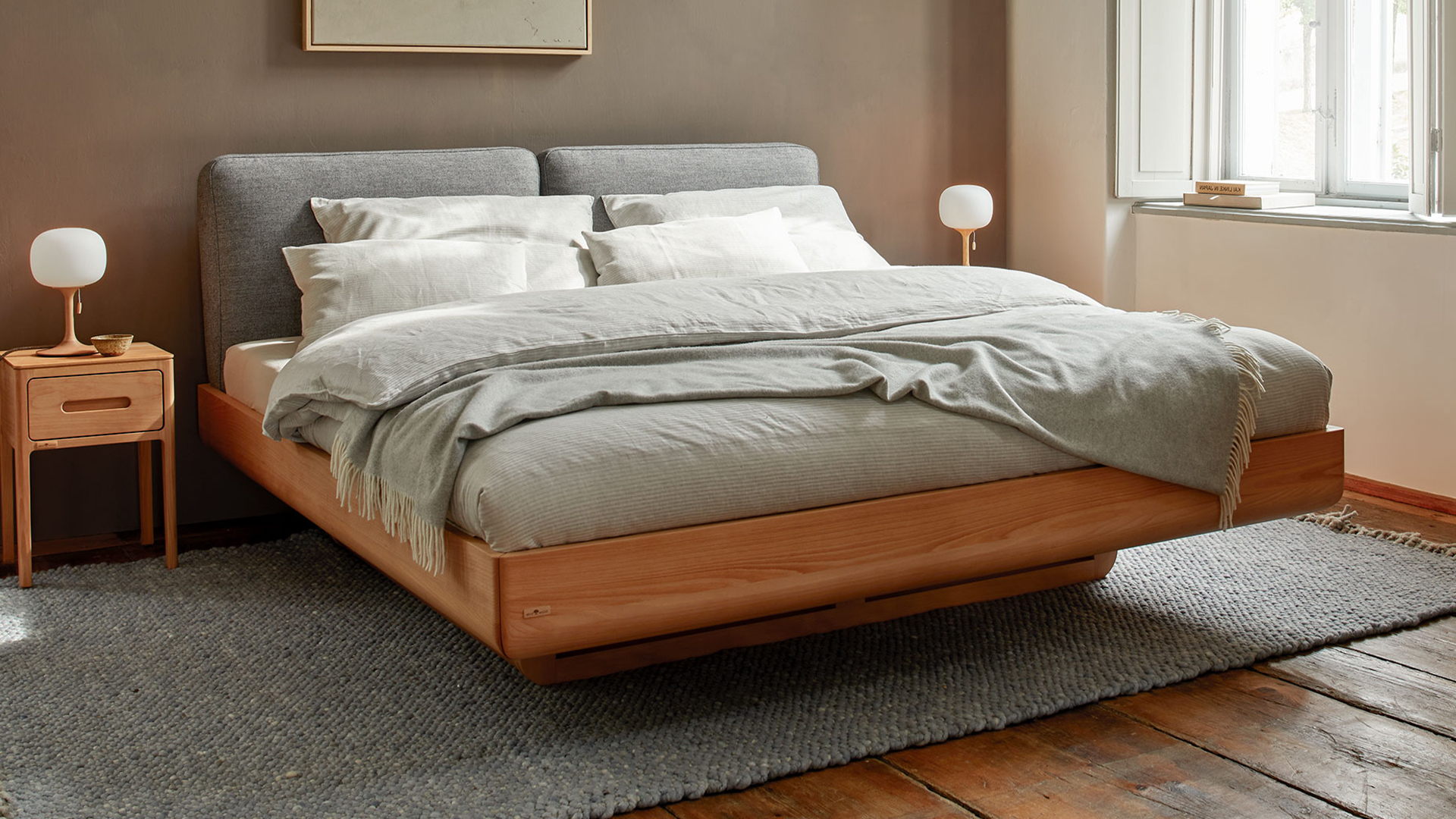 Modernes Schlafzimmer mit Polsterbett und warmem Holz in ruhiger Atmosphäre