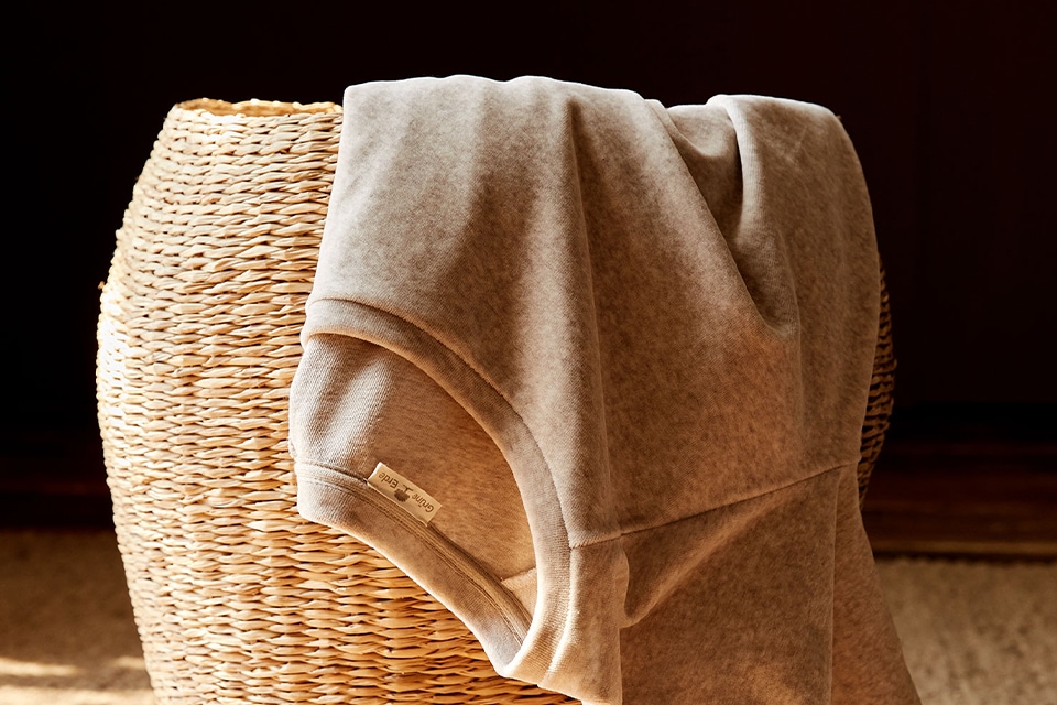 Wäschekorb mit Kleidung im warmen Sonnenlicht auf Holzboden