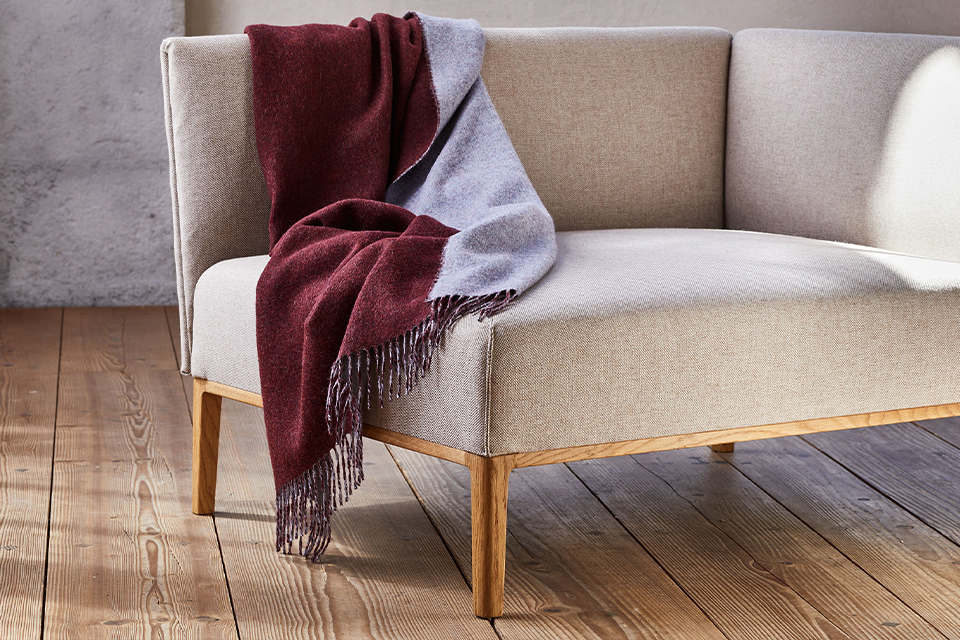 Helles Sofa mit Decke in gemütlichem Wohnraum