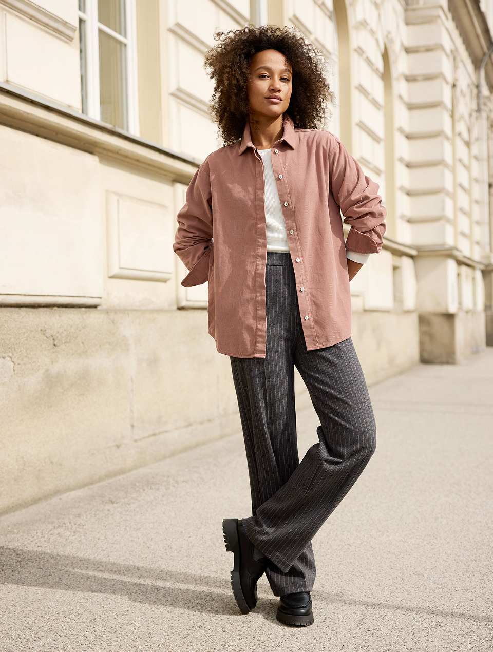 Frau trägt rosafarbene Bluse und graue Hose