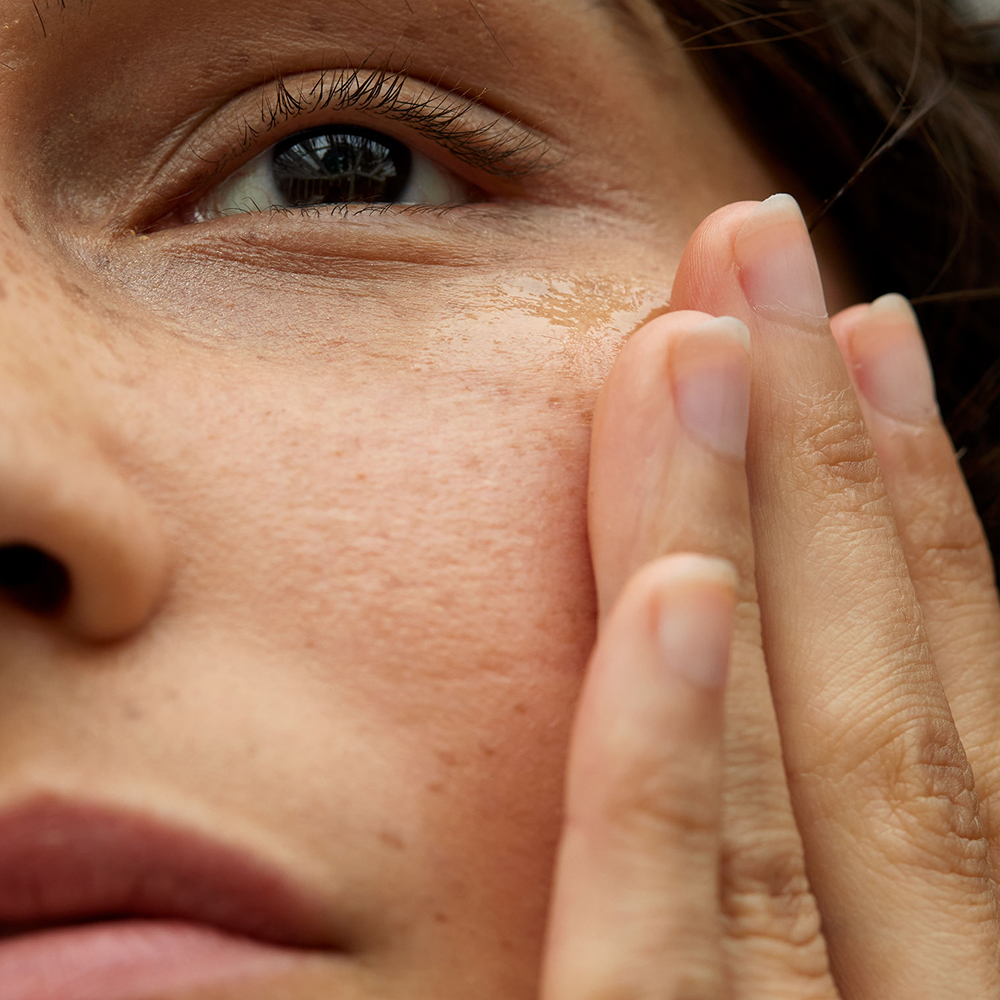 Linke Hälfte eines Frauengesichtes mit einer Hand an der Wange