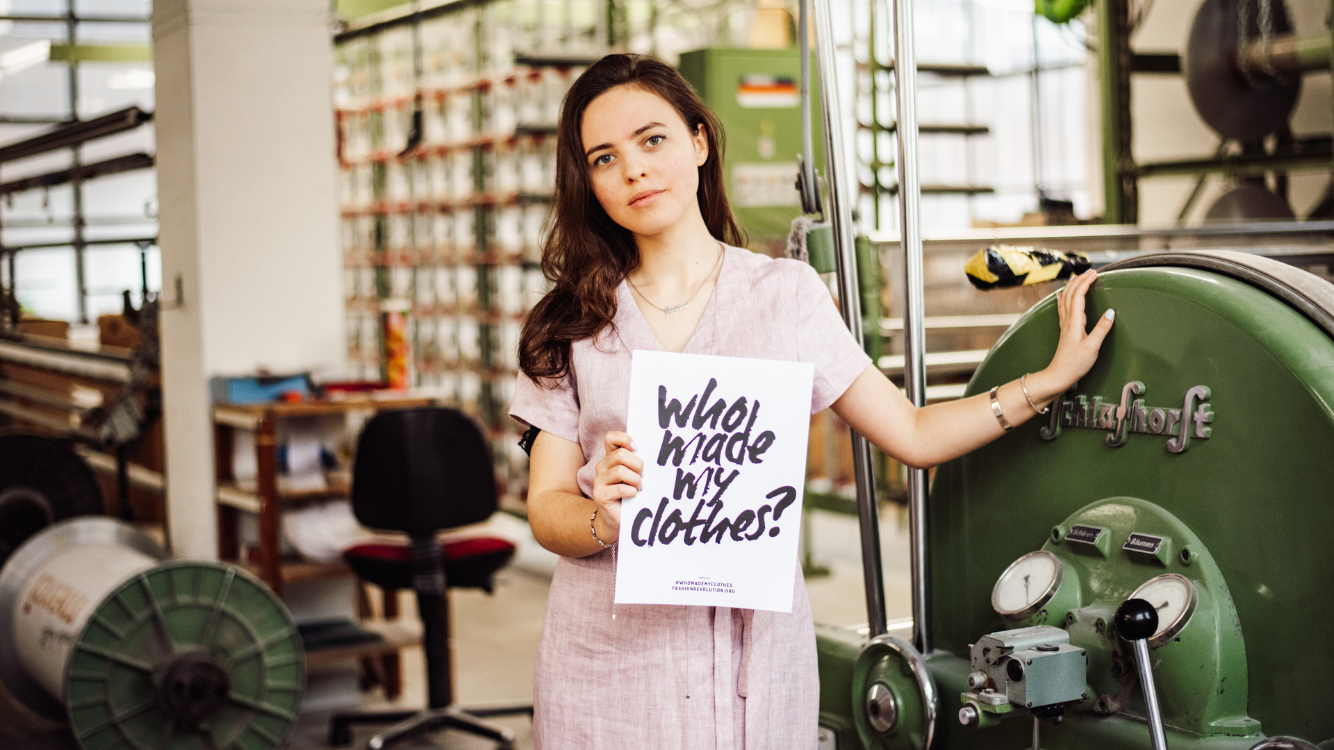 Frau trägt ein Schild mit der Aufschrift who made my clothes