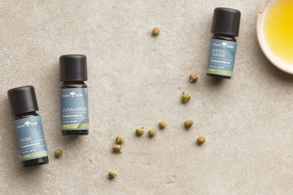 Ätherische Öle und eine Schale mit Öl nebeneinander angeordnet