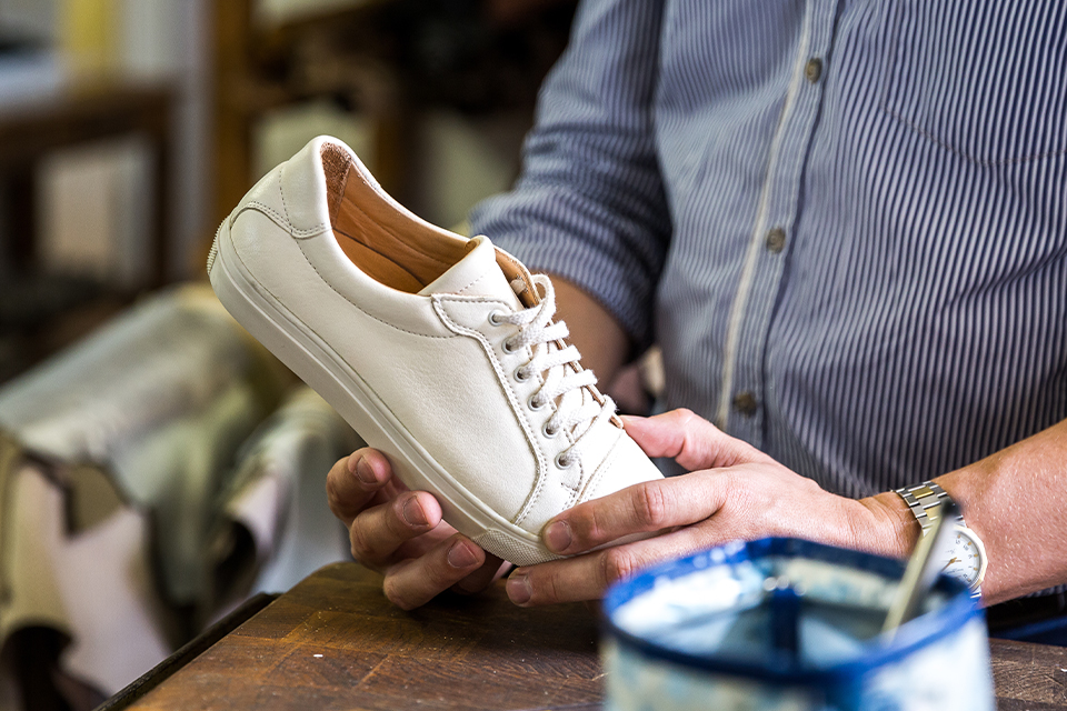 Ein Mann hält einen weißen Lederschuh in den Händen