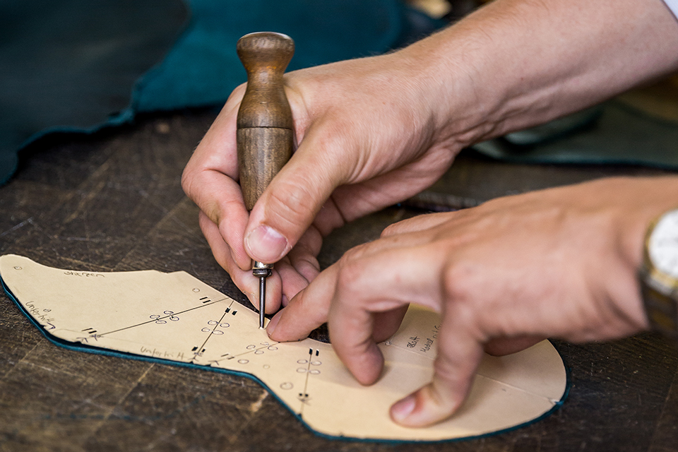 Der Schuhmacher schneidet die Sohle zu