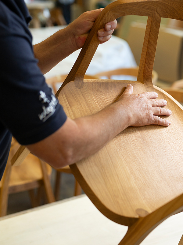 Mann hält das Holzgestell eines Stuhls in den Händen