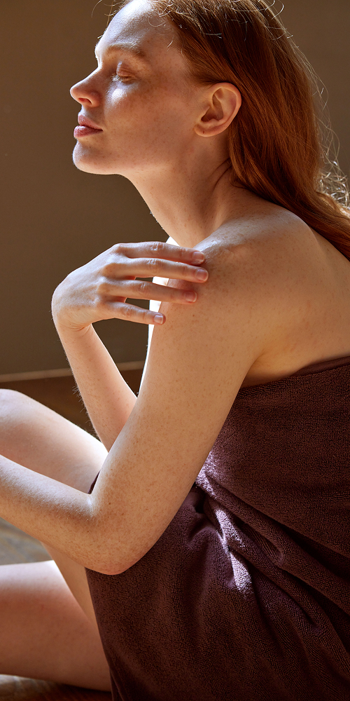 Frau die in ein Badetuch gewickelt ist sitzt am Boden