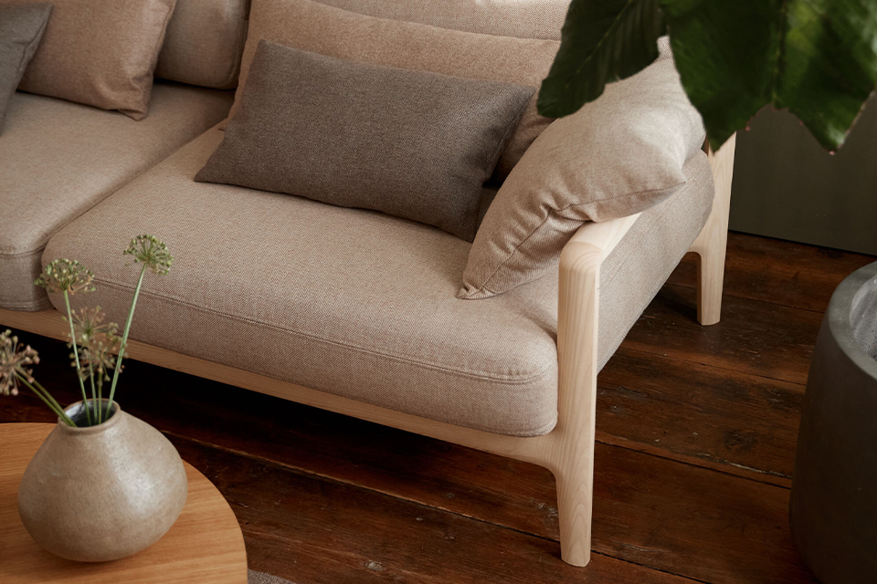 Helles Sofa mit Kissen neben kleinem Tisch mit Vase