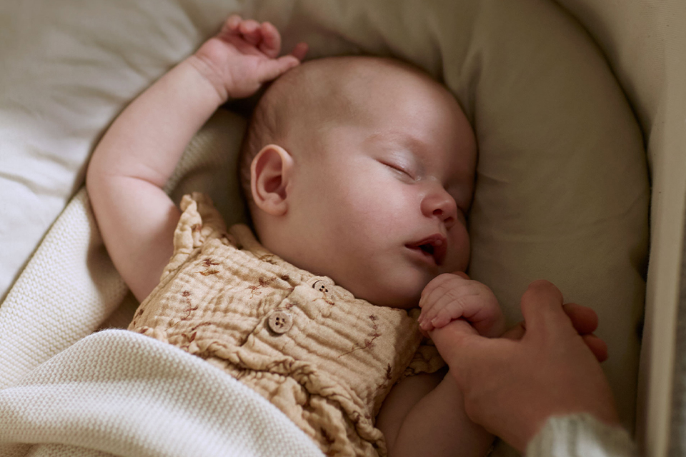 Baby mit Kuschelschlange schlafend in einer Babywiege liegend