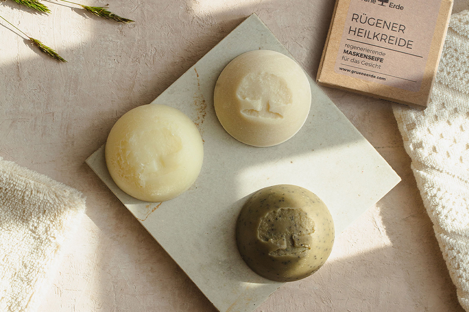 Zwei feste Seifen und ein Bürstchen mit einem dekorativen Blümchen