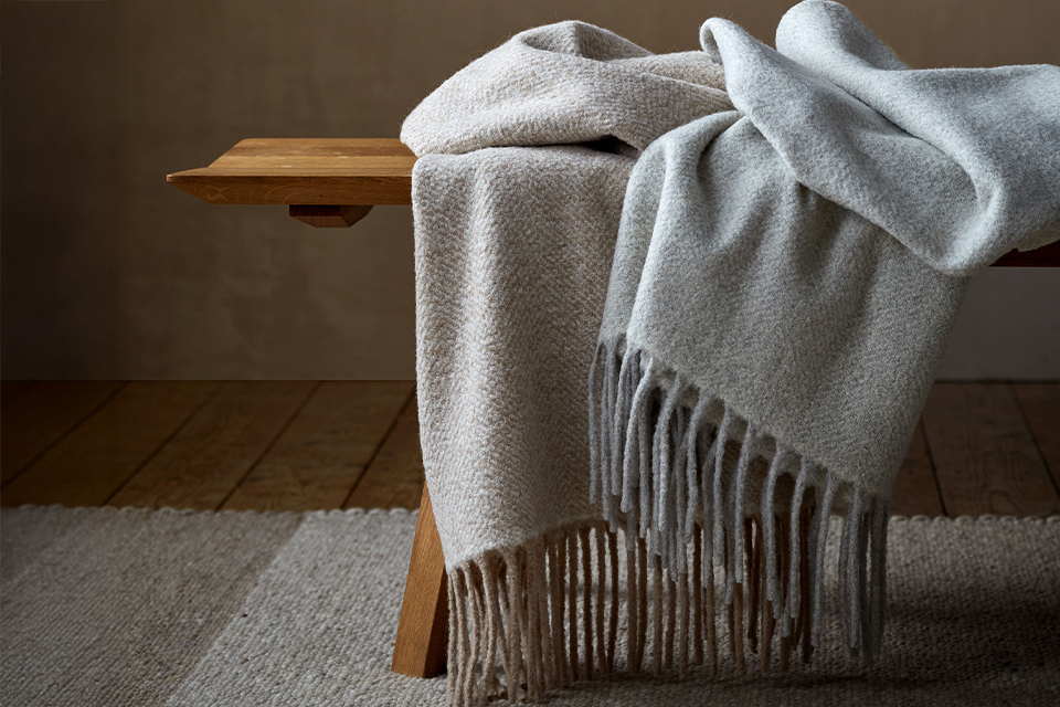 Graue Wohndecken auf einer Holzbank liegend