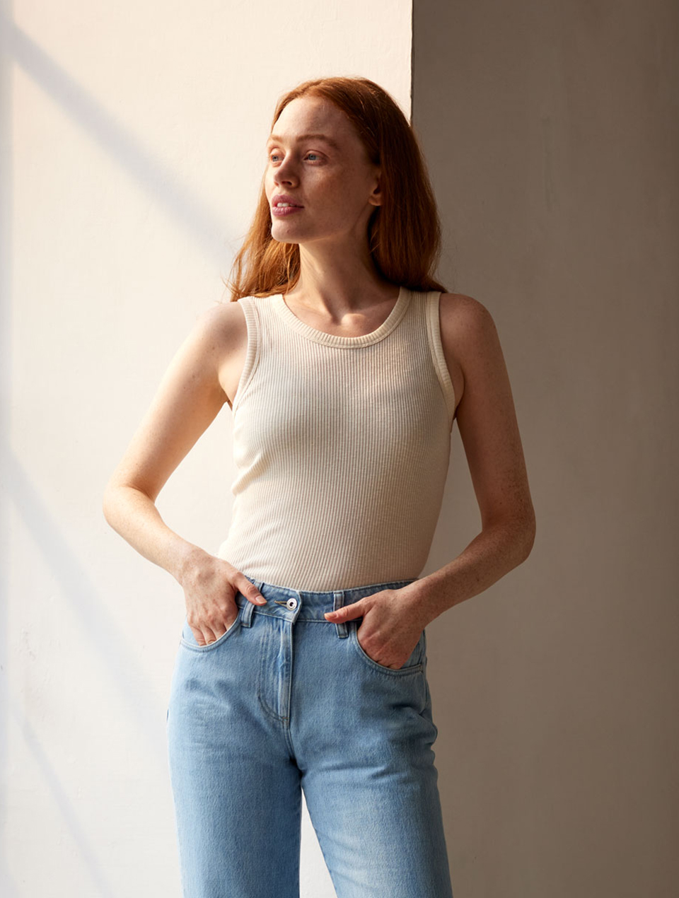 Frau trägt helles Trägertop und Jeans im Lichteinfall