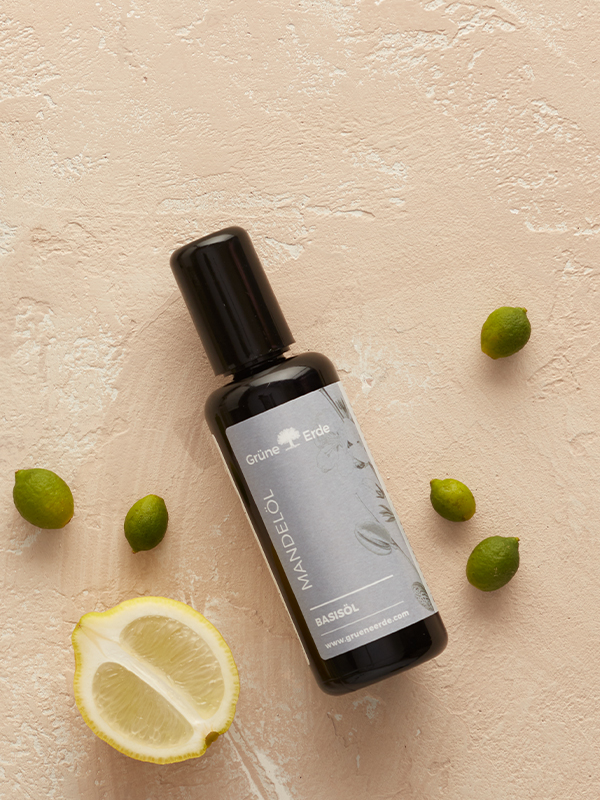 Basisöl und ätherische Öle mit Knospen und einer Zitrone dekorativ angeordnet