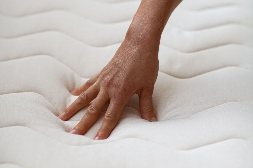 Eine Hand drückt auf eine ökologische Matratze