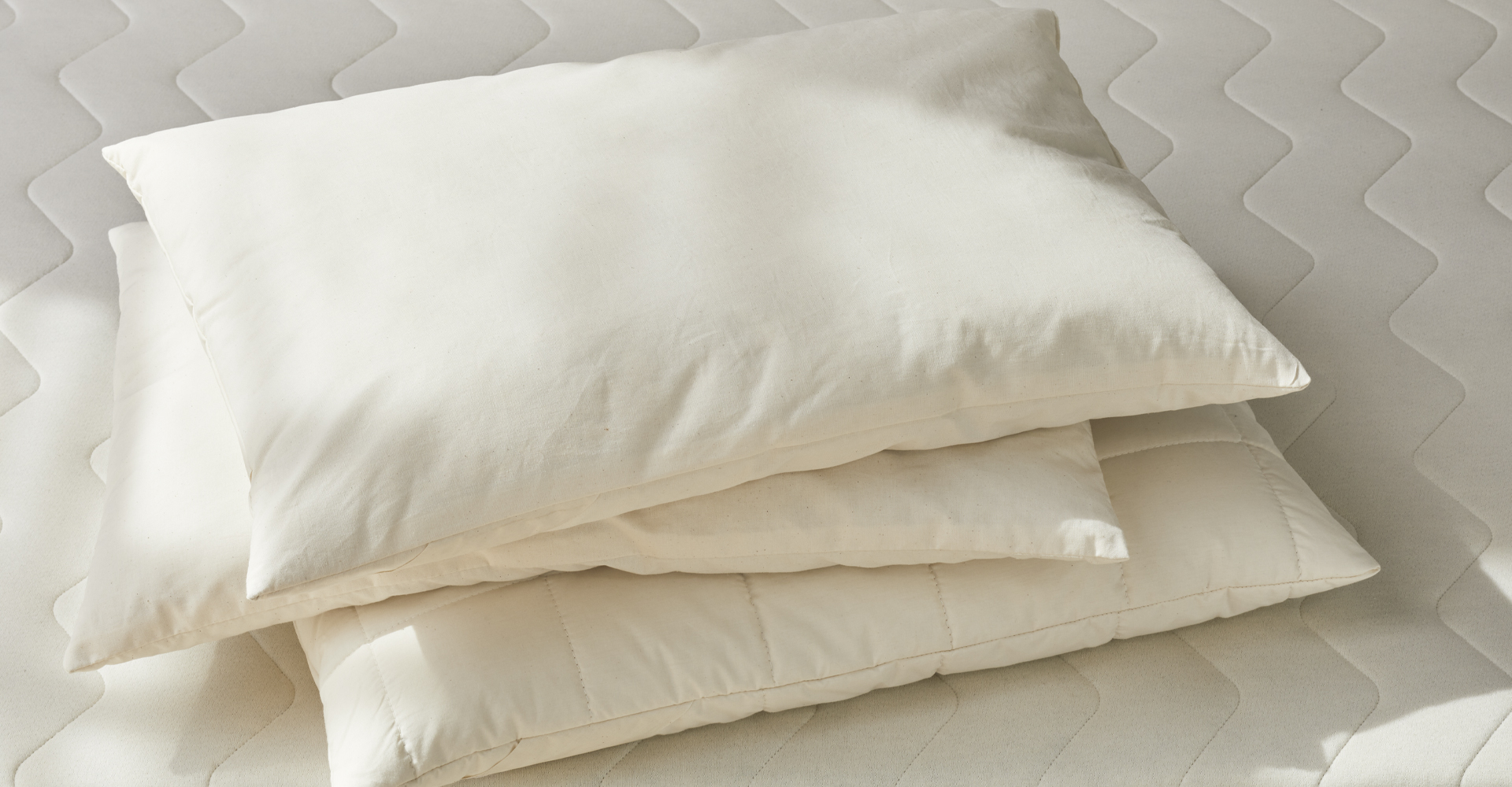 Drei hochwertige Schlafkissen liegen auf einer Naturmatratze
