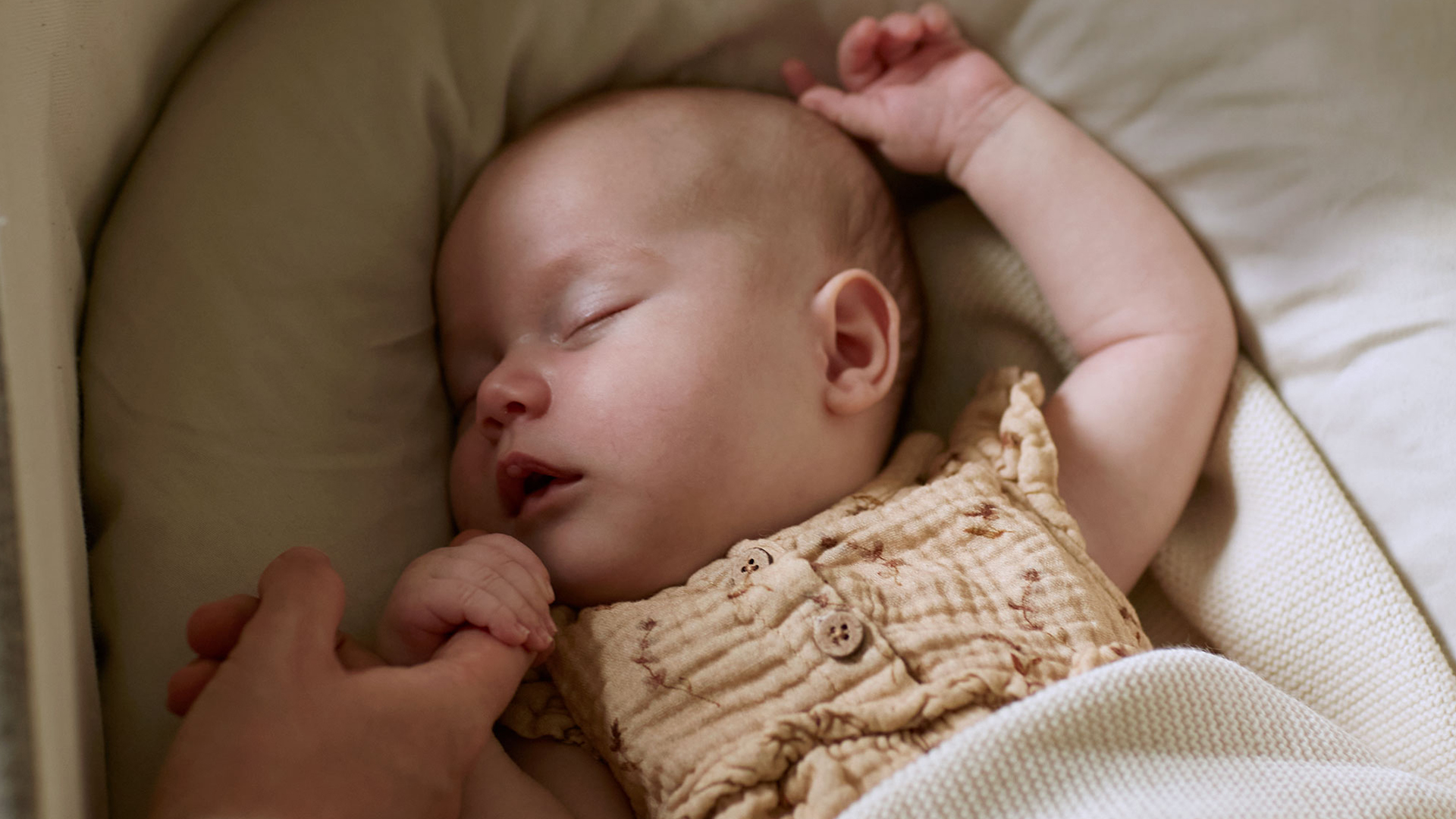 Baby mit Kuschelschlange schlafend in einer Babywiege liegend